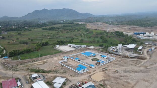 Aerial view of the Dhoho International Airport construction site with blue roofed facilities surrounding green fields and mountains in the distance in Kecamatan Grogol Jawa Timur Indonesia. Aerial view of the Dhoho International Airport construction site with blue roofed facilities surrounding green fields and mountains in the distance in Kecamatan Grogol Jawa Timur Indonesia.