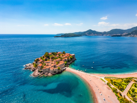 Aerial view of the historic islet village of Sveti Stefan with terracotta roofed buildings connected by a sandy isthmus Sveti Stefan Budva Municipality Montenegro.