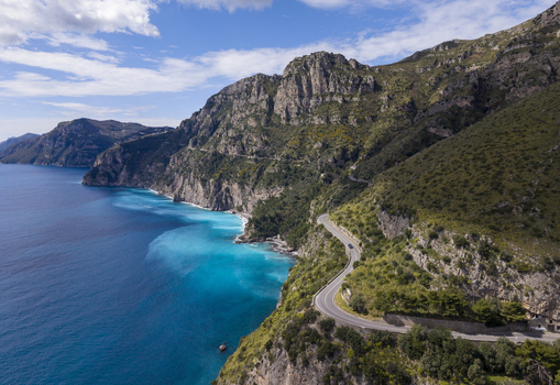 Aerial view of turquoise waters meet rugged cliffs along a winding coastal road a symphony of blues and greens under a vast sky Amalfi Campania Italy. Aerial view of turquoise waters meet rugged cliffs along a winding coastal road a symphony of blues and greens under a vast sky Amalfi Campania Italy.