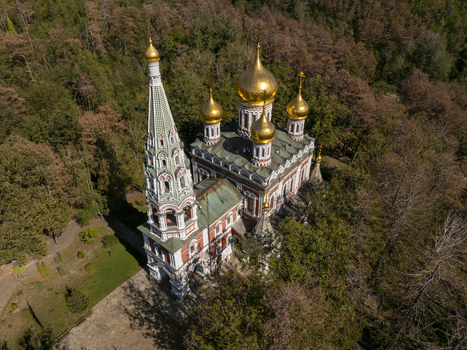 Aerial view of Shipka Memorial Church with its golden domes and tall bell tower surrounded by dense forest in autumn in Shipka Stara Zagora Bulgaria. Aerial view of Shipka Memorial Church with its golden domes and tall bell tower surrounded by dense forest in autumn in Shipka Stara Zagora Bulgaria.