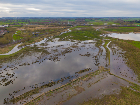 Aerial view of Doxey Marshes featuring expansive wetlands winding water channels and grassy banks with a railway line in the distance in Stafford England United Kingdom. Aerial view of Doxey Marshes featuring expansive wetlands winding water channels and grassy banks with a railway line in the distance in Stafford England United Kingdom.