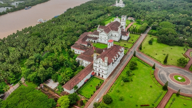 Aerial view of the Church of St. Francis of Assisi surrounded by lush green palm trees manicured lawns and a winding river in Old Goa Goa India. Aerial view of the Church of St. Francis of Assisi surrounded by lush green palm trees manicured lawns and a winding river in Old Goa Goa India.