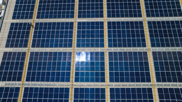 Aerial view of solar panels installed on a warehouse roof with a worker visible for scale in Bhiwandi Maharashtra India. Aerial view of solar panels installed on a warehouse roof with a worker visible for scale in Bhiwandi Maharashtra India.