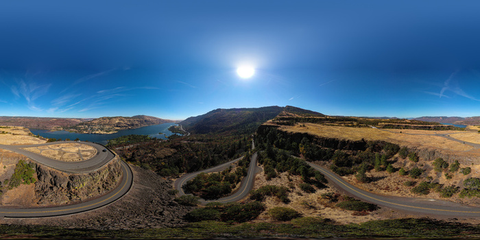 Aerial view of a winding road through a rugged canyon landscape with dry golden hills and a river under a clear blue sky in Metro Vancouver A British Columbia Canada.