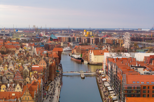 Aerial view of the Motlawa river flowing through the historic old town of Gdansk featuring red roofed buildings a ferris wheel and industrial cranes in Gdansk Wojewodztwo pomorskie Poland. Aerial view of the Motlawa river flowing through the historic old town of Gdansk featuring red roofed buildings a ferris wheel and industrial cranes in Gdansk Wojewodztwo pomorskie Poland.