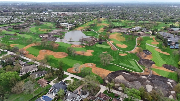 Aerial view of a golf course under renovation with green fairways sand bunkers and a small pond surrounded by suburban houses and trees in Chicago Illinois United States.