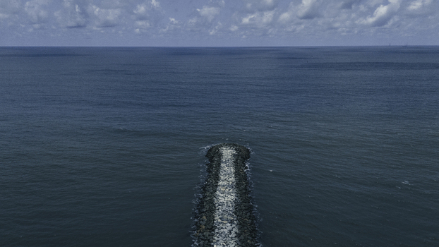 Aerial view of a stone breakwater extending into the deep blue Atlantic Ocean under a cloudy sky in Lekki Lagos Nigeria. Aerial view of a stone breakwater extending into the deep blue Atlantic Ocean under a cloudy sky in Lekki Lagos Nigeria.
