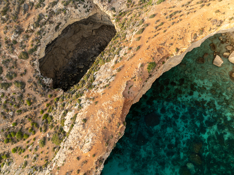 Aerial view of rugged cliffs meet the turquoise sea revealing hidden caves and sun kissed rocks creating a stunning contrast of colors and textures Blue lagoon Comino Malta. Aerial view of rugged cliffs meet the turquoise sea revealing hidden caves and sun kissed rocks creating a stunning contrast of colors and textures Blue lagoon Comino Malta.