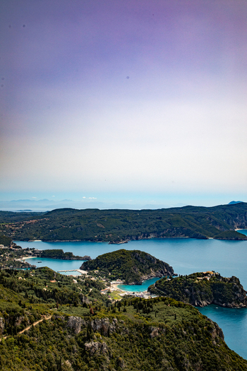 Aerial view of the turquoise waters of the Ionian Sea surrounding the lush green hills and rocky coastline of Corfu Ionian Islands Greece. Aerial view of the turquoise waters of the Ionian Sea surrounding the lush green hills and rocky coastline of Corfu Ionian Islands Greece.