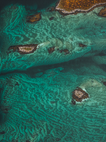 Aerial view of the turquoise waters and rocky islands of Senja showcasing the vibrant coastal landscape in Senja Troms Norway.