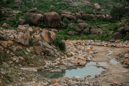 View of the rocky landscape with large granite boulders a small pool of water and scattered vegetation Jos North Plateau Nigeria. View of the rocky landscape with large granite boulders a small pool of water and scattered vegetation Jos North Plateau Nigeria.