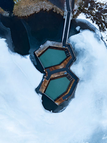 Aerial view of Vok Baths featuring geothermal pools with wooden walkways surrounded by frozen lake water and snow in Egilsstadir Mulathing Iceland. Aerial view of Vok Baths featuring geothermal pools with wooden walkways surrounded by frozen lake water and snow in Egilsstadir Mulathing Iceland.