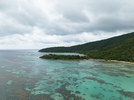 Aerial view of the tranquil Annora beach where turquoise waters meet the lush green coastline under a cloudy sky Karimunjawa Jawa Tengah Indonesia.