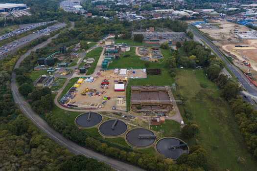 Aerial view of a wastewater treatment plant with circular sedimentation tanks aeration basins and industrial infrastructure surrounded by green trees in the United Kingdom. Aerial view of a wastewater treatment plant with circular sedimentation tanks aeration basins and industrial infrastructure surrounded by green trees in the United Kingdom.