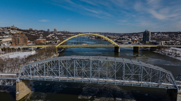 Aerial view of the Big Mac Bridge and Taylor Southgate Bridge spanning the icy Ohio River with snow covered banks and urban buildings under a clear blue sky in Cincinnati Ohio United States. Aerial view of the Big Mac Bridge and Taylor Southgate Bridge spanning the icy Ohio River with snow covered banks and urban buildings under a clear blue sky in Cincinnati Ohio United States.