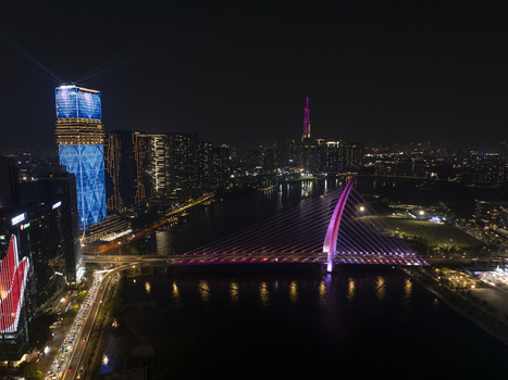 Aerial view of Thu Thiem 2 Bridge illuminated with pink lights and modern skyscrapers with LED displays at night Ho Chi Minh City Ho Chi Minh Vietnam. Aerial view of Thu Thiem 2 Bridge illuminated with pink lights and modern skyscrapers with LED displays at night Ho Chi Minh City Ho Chi Minh Vietnam.
