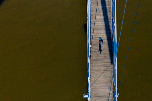 Aerial view of the Lila Brucke bridge with a cyclist crossing the wooden deck over the river in Forchheim Bavaria Germany. Aerial view of the Lila Brucke bridge with a cyclist crossing the wooden deck over the river in Forchheim Bavaria Germany.