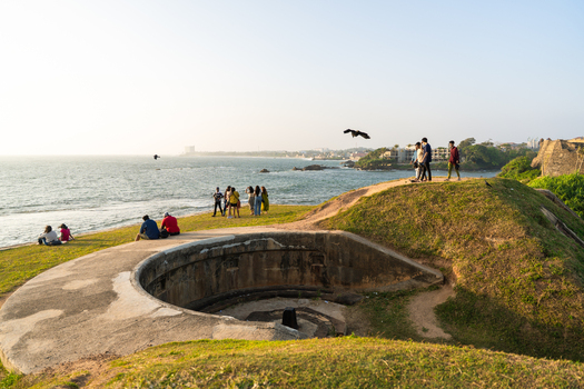 View of people walking on the historic ramparts of Galle Fort with a stone bastion and the ocean in Galle Southern Province Sri Lanka.