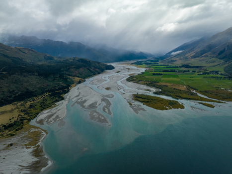 Aerial view of braided river carving through valleys meeting the lake s tranquil expanse under a sky heavy with clouds Glenorchy Otago Region New Zealand. Aerial view of braided river carving through valleys meeting the lake s tranquil expanse under a sky heavy with clouds Glenorchy Otago Region New Zealand.