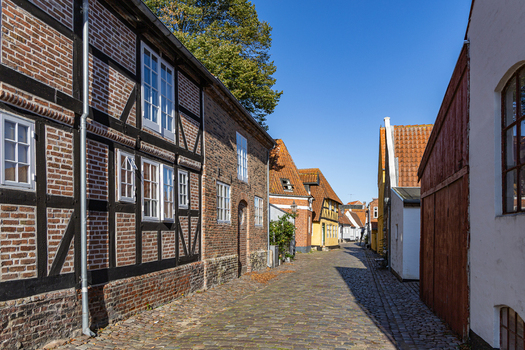 View of historic half timbered brick houses along a narrow cobblestone street under a clear blue sky in the old town of Ribe Denmark. View of historic half timbered brick houses along a narrow cobblestone street under a clear blue sky in the old town of Ribe Denmark.