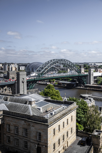 Aerial view of the iconic Tyne Bridge spanning the River Tyne with historic stone buildings in the foreground and the modern cityscape of Newcastle upon Tyne England United Kingdom. Aerial view of the iconic Tyne Bridge spanning the River Tyne with historic stone buildings in the foreground and the modern cityscape of Newcastle upon Tyne England United Kingdom.