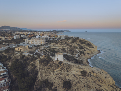 Aerial view of the Santuari iber i roma de la Malladeta tower on a rugged cliff overlooking the Mediterranean Sea at sunset in La Vila Joiosa Comunidad Valenciana Spain. Aerial view of the Santuari iber i roma de la Malladeta tower on a rugged cliff overlooking the Mediterranean Sea at sunset in La Vila Joiosa Comunidad Valenciana Spain.