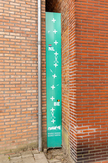 View of the border marker sign between the Netherlands and Belgium featuring symbols and text for Baarle Nassau and Baarle Hertog located in Baarle Nassau North Brabant Netherlands.