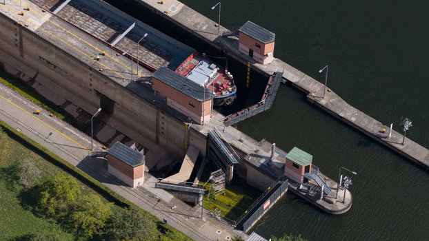 Aerial view of the Rockenau lock on the Neckar river with a barge inside the chamber surrounded by concrete walls and green riverbanks in Eberbach Baden Wurttemberg Germany. Aerial view of the Rockenau lock on the Neckar river with a barge inside the chamber surrounded by concrete walls and green riverbanks in Eberbach Baden Wurttemberg Germany.