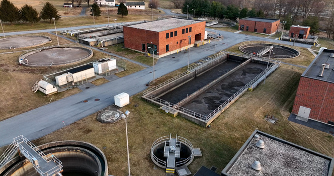 Aerial view of a wastewater treatment plant with circular sedimentation tanks and rectangular aeration basins surrounded by brick buildings and grassy grounds in Lititz Pennsylvania United States. Aerial view of a wastewater treatment plant with circular sedimentation tanks and rectangular aeration basins surrounded by brick buildings and grassy grounds in Lititz Pennsylvania United States.