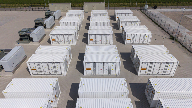 Aerial view of the Battery Energy Storage System at Wind Park featuring rows of white shipping containers used for energy storage on a paved site in Dronten Flevoland Netherlands. Aerial view of the Battery Energy Storage System at Wind Park featuring rows of white shipping containers used for energy storage on a paved site in Dronten Flevoland Netherlands.