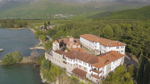Aerial view of the historic Saint Naum Monastery on a cliff overlooking Lake Ohrid surrounded by dense forests and mountains in the Municipality of Ohrid North Macedonia.