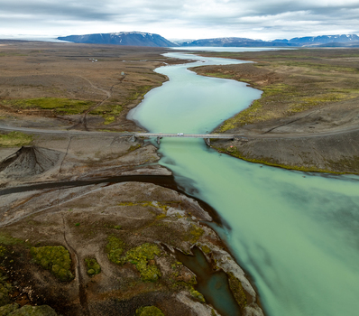 Aerial view of Kerlingarfjoll mountains and a glacial river flowing under a bridge through the rugged volcanic landscape of Hrunamannahreppur Iceland. Aerial view of Kerlingarfjoll mountains and a glacial river flowing under a bridge through the rugged volcanic landscape of Hrunamannahreppur Iceland.