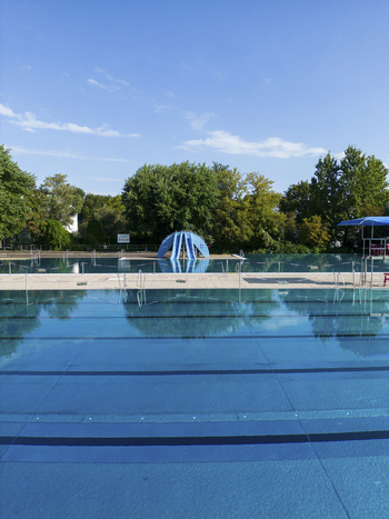 Aerial view of public pools surrounded by trees and blue water under a clear sky Wedding Germany.