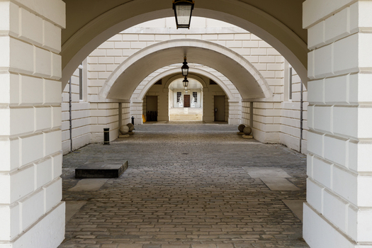View of the historic stone archways at Horse Guards Parade with cobblestone flooring and hanging lanterns in London England United Kingdom.