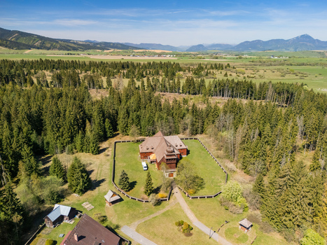 Aerial view of the Wooden Articular Church of Svaty Kriz surrounded by a wooden fence and lush evergreen forest Svaty Kriz Zilinsky kraj Slovakia.