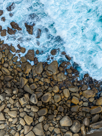 Aerial view of rugged rocky coastline with crashing turquoise waves and sea foam along the shore in Torndirrup Western Australia Australia. Aerial view of rugged rocky coastline with crashing turquoise waves and sea foam along the shore in Torndirrup Western Australia Australia.