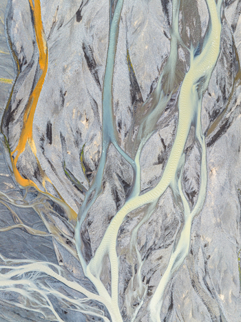 Aerial view of a braided river with glacial meltwater channels flowing through dark volcanic sediment in Iceland. Aerial view of a braided river with glacial meltwater channels flowing through dark volcanic sediment in Iceland.