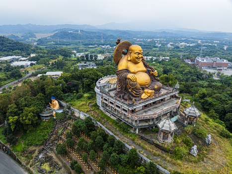 Aerial view of a large golden Maitreya Buddha statue overlooking the lush green hills and temple grounds in Jiuru Township Pingtung County Taiwan. Aerial view of a large golden Maitreya Buddha statue overlooking the lush green hills and temple grounds in Jiuru Township Pingtung County Taiwan.