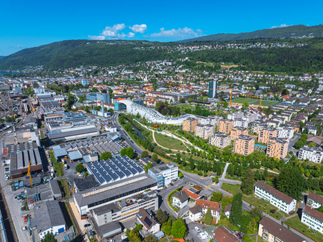 Aerial view of the modern architecture of the Swatch headquarters industrial zones and residential areas surrounded by green parks and hills in Biel Bienne Canton of Bern Switzerland.