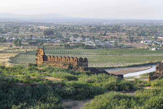 View of the historic stone walls of Rohtas Fort overlooking the rural landscape agricultural fields and a winding stream in Dina Punjab Pakistan. View of the historic stone walls of Rohtas Fort overlooking the rural landscape agricultural fields and a winding stream in Dina Punjab Pakistan.