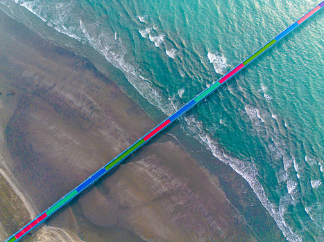 Aerial view of a vibrant long bridge stretching across the meeting point of sandy shores and turquoise waves Cox s Bazar Chittagong Division Bangladesh.