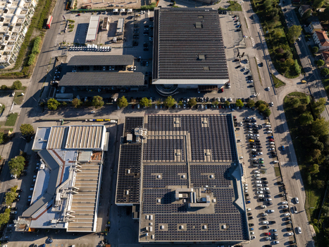 Aerial view of industrial buildings with extensive solar panel arrays on the rooftops parking lots filled with cars and surrounding roads in Ancona Marche Italy. Aerial view of industrial buildings with extensive solar panel arrays on the rooftops parking lots filled with cars and surrounding roads in Ancona Marche Italy.