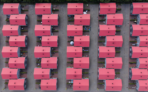 Aerial view of prefabricated housing for migrant and seasonal workers with rows of identical houses featuring bright red roofs in Swifterbant Flevoland Netherlands. Aerial view of prefabricated housing for migrant and seasonal workers with rows of identical houses featuring bright red roofs in Swifterbant Flevoland Netherlands.
