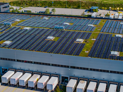 Aerial view of the Logistikzentrum Allhaming with a green roof covered in solar panels loading docks and trucks parked at the facility Allhaming Oberosterreich Austria. Aerial view of the Logistikzentrum Allhaming with a green roof covered in solar panels loading docks and trucks parked at the facility Allhaming Oberosterreich Austria.