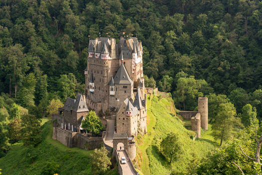 View of Eltz Castle a medieval fortress with stone towers and timber framed structures nestled among lush green hills and dense forest in Wierschem Rhineland Palatinate Germany. View of Eltz Castle a medieval fortress with stone towers and timber framed structures nestled among lush green hills and dense forest in Wierschem Rhineland Palatinate Germany.