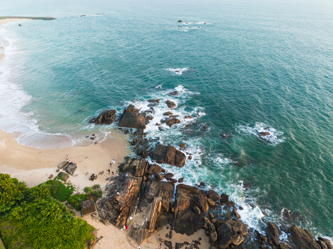 Aerial view of a sandy beach and rocky coastline with turquoise ocean waves crashing against dark stones and lush green vegetation Galle Southern Province Sri Lanka. Aerial view of a sandy beach and rocky coastline with turquoise ocean waves crashing against dark stones and lush green vegetation Galle Southern Province Sri Lanka.