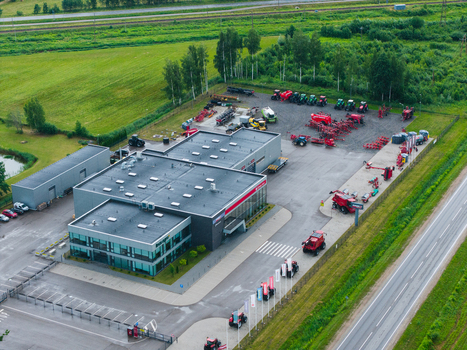 Brankas Latvia 04 July 2026 Aerial view of a modern agricultural machinery sales and service center with a large showroom warehouse and a yard filled with tractors. Brankas Latvia 04 July 2026 Aerial view of a modern agricultural machinery sales and service center with a large showroom warehouse and a yard filled with tractors.
