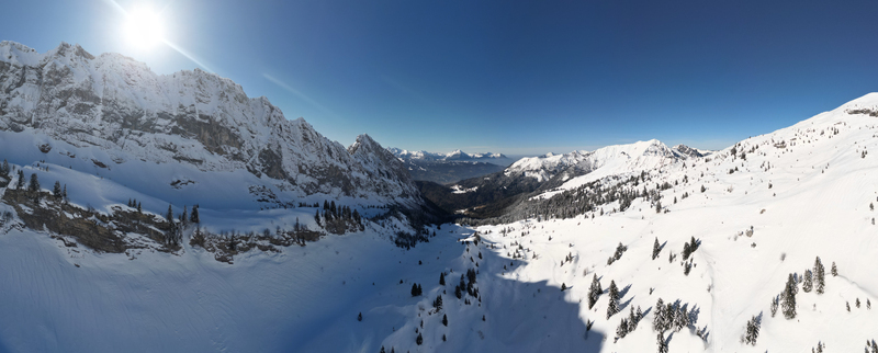 Aerial view of snow laden mountains under a radiant sun casting long shadows across the pristine white landscape Samoëns Auvergne Rhône Alpes France. Aerial view of snow laden mountains under a radiant sun casting long shadows across the pristine white landscape Samoëns Auvergne Rhône Alpes France.