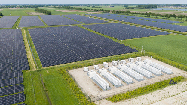 Aerial view of a large solar farm with rows of photovoltaic panels and a battery energy storage system facility surrounded by green fields in Wanneperveen Overijssel Netherlands. Aerial view of a large solar farm with rows of photovoltaic panels and a battery energy storage system facility surrounded by green fields in Wanneperveen Overijssel Netherlands.