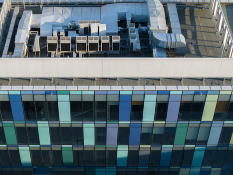 Aerial view of a modern data center building featuring a colorful glass facade and industrial HVAC cooling units on the rooftop in Krakow Lesser Poland Voivode Poland. Aerial view of a modern data center building featuring a colorful glass facade and industrial HVAC cooling units on the rooftop in Krakow Lesser Poland Voivode Poland.